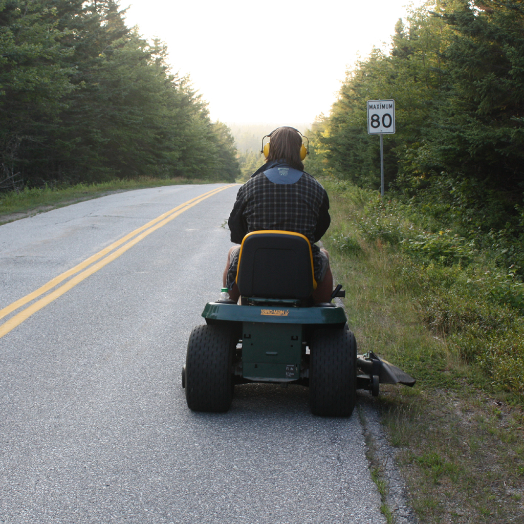 A man riding a lawn mower on a road