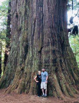 Morgan and her husband standing in front of a tall tree